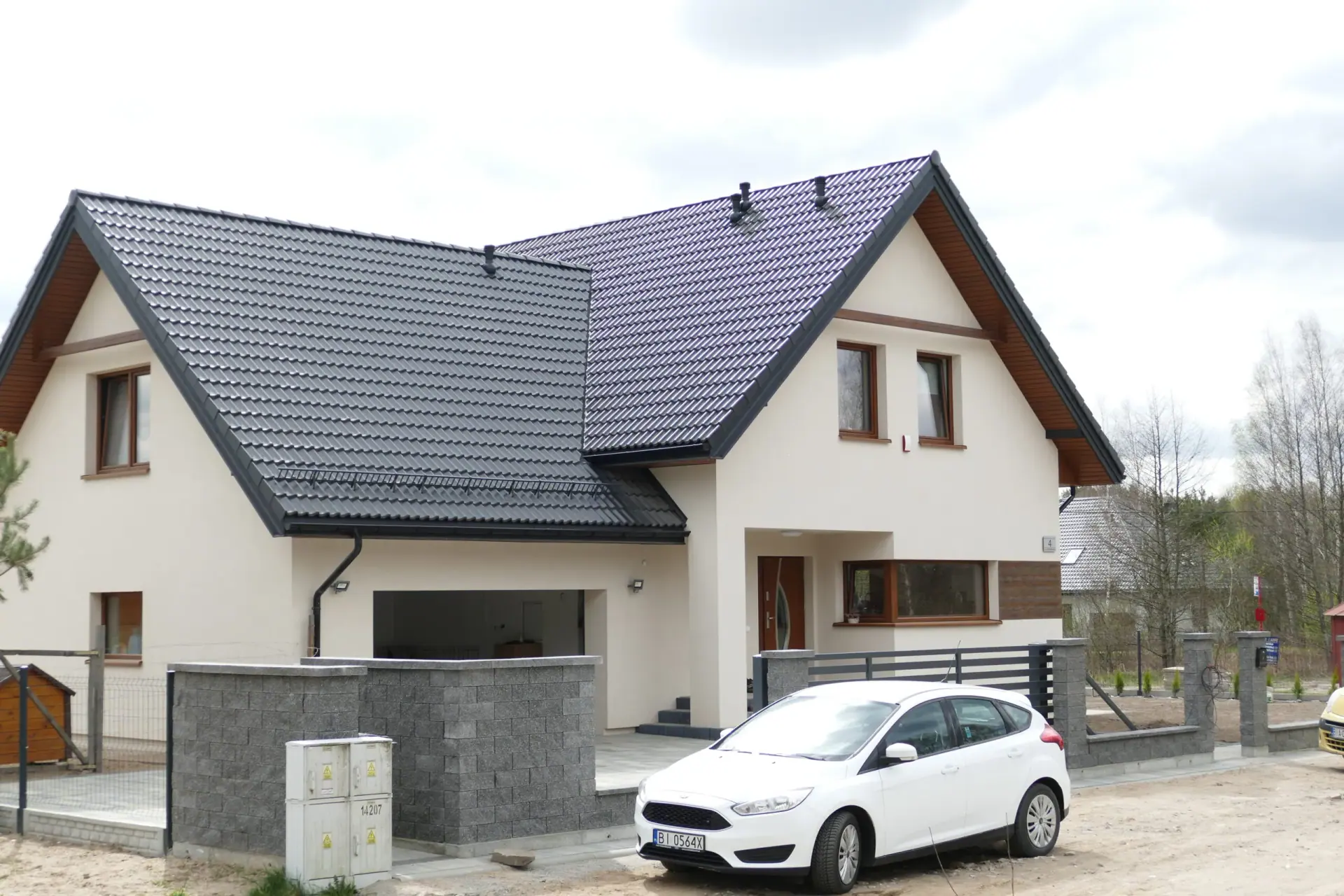 Dach dwuspadowy białego domu z przylegającym garażem