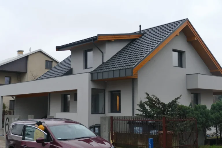 Dom o rozbudowanej bryle z ciemnym dachem