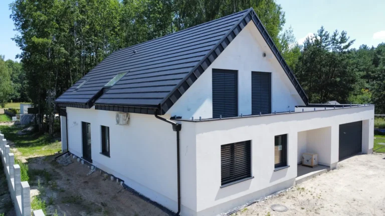 Ciemny dach z oknami połaciowymi nad jasnym domem