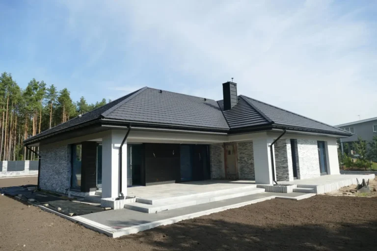 Ciemny dach nad domem z płaską częścią garażową